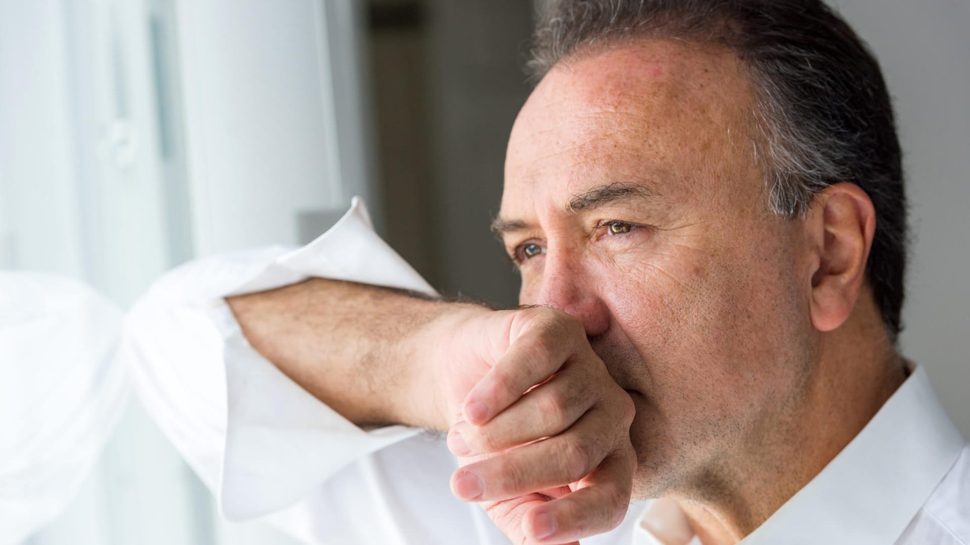 Mann schaut aus dem Fenster: Menschen mit bereits vorhandenen psychischen oder kognitiven Störungen sind stärker von Depressionen betroffen.