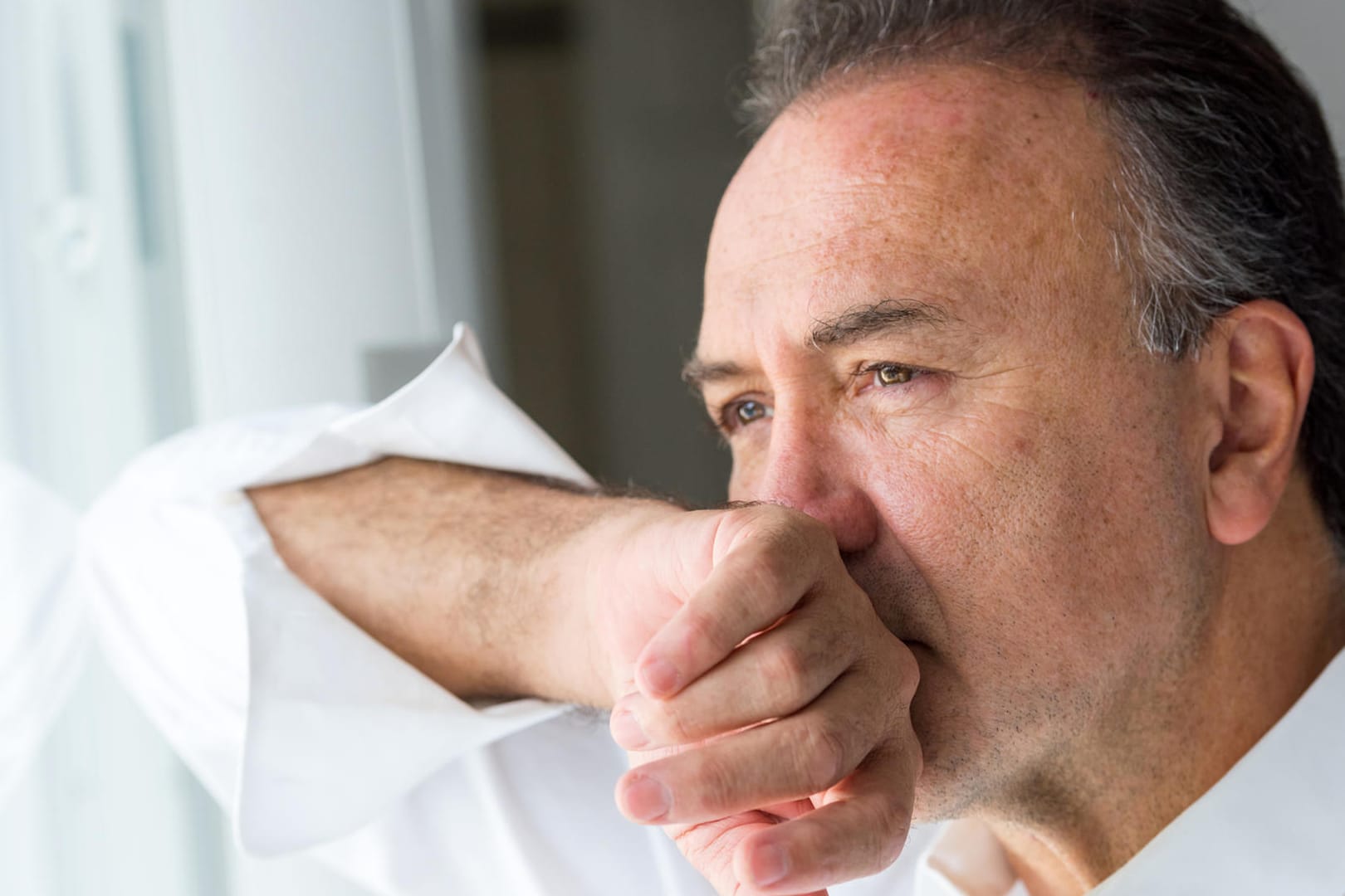 Mann schaut aus dem Fenster: Menschen mit bereits vorhandenen psychischen oder kognitiven Störungen sind stärker von Depressionen betroffen.