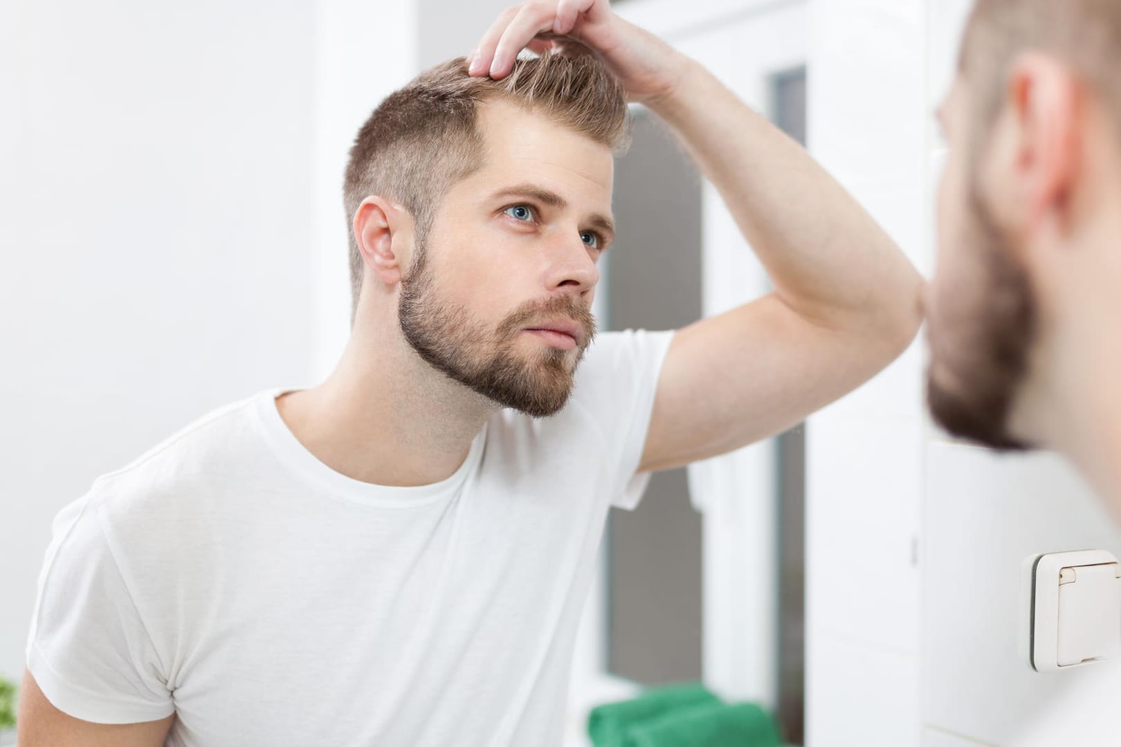 Der erste Haarausfall zeigt sich bei Männern oft in Geheimratsecken.