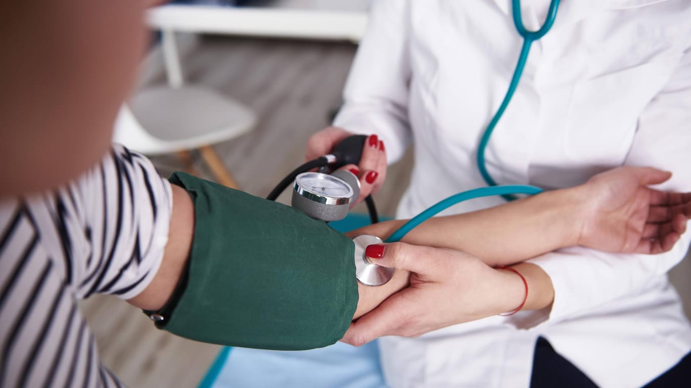 Ärztin misst den Blutdruck einer Patientin: Wird eine Hypertonie nicht behandelt, drohen Krankheiten, die das Herz-Kreislauf-System belasten.