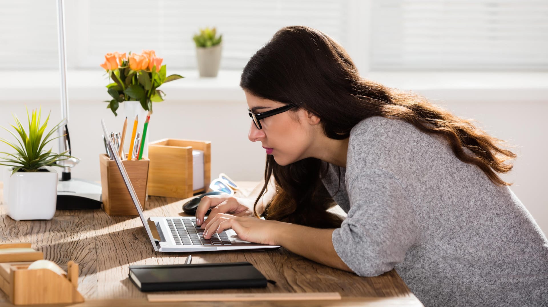 Eine Frau beugt sich über ihren Laptop: Was steckt hinter der Fehlermeldung "Netzwerk-Zeitüberschreitung"?