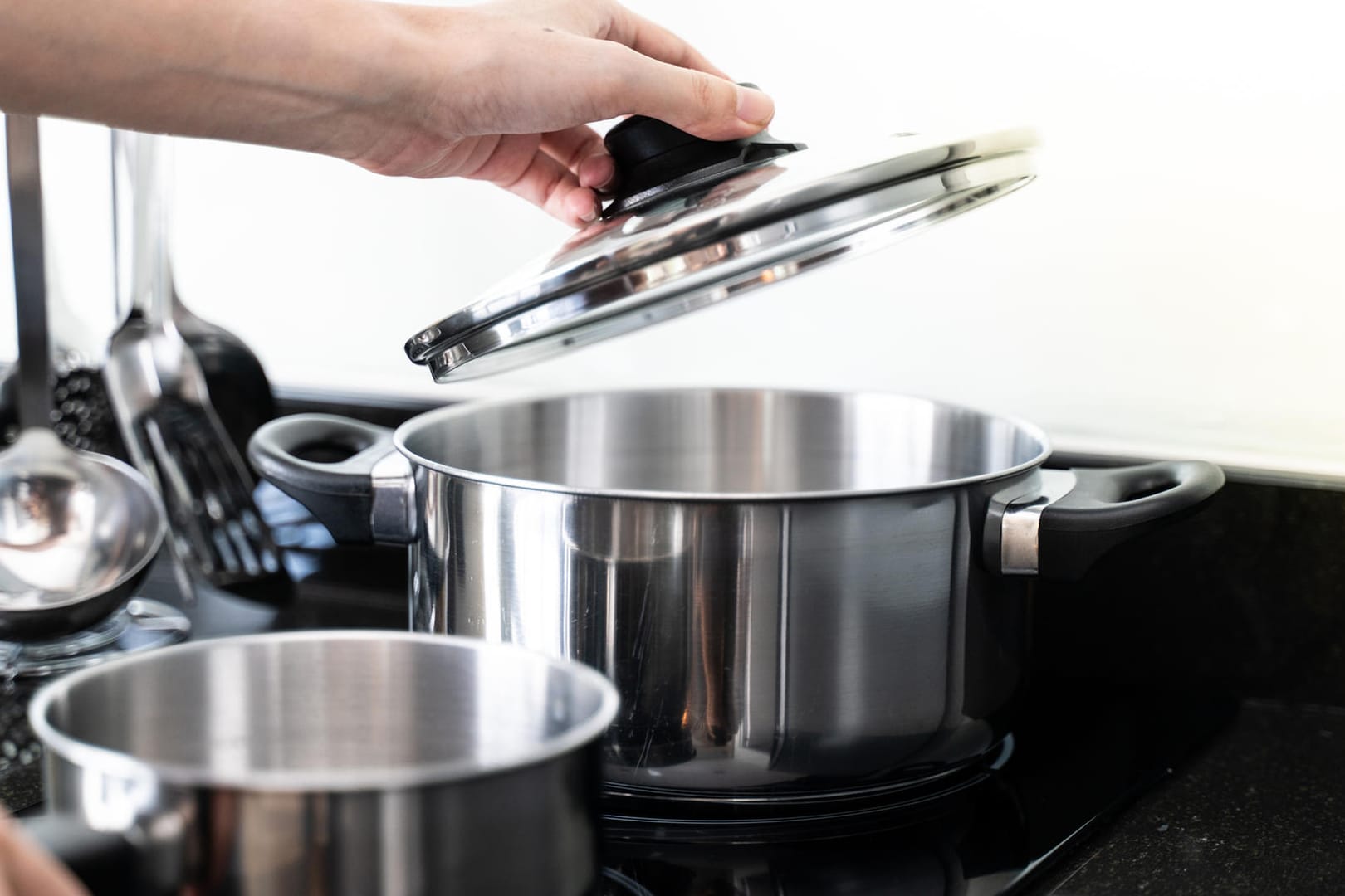 Töpfe auf einem Herd: Mit einem Deckel auf dem Topf sparen Sie beim Kochen Energie.