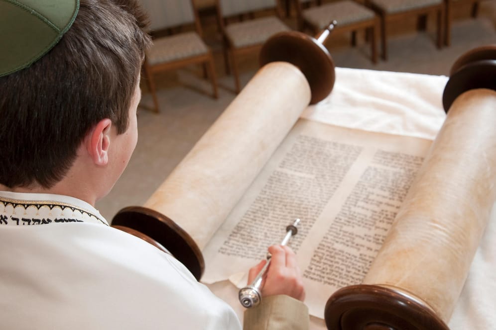 Junger Mann mit Kippa liest die Tora: Es gibt sehr viele verschiedene jüdische Feiertage.