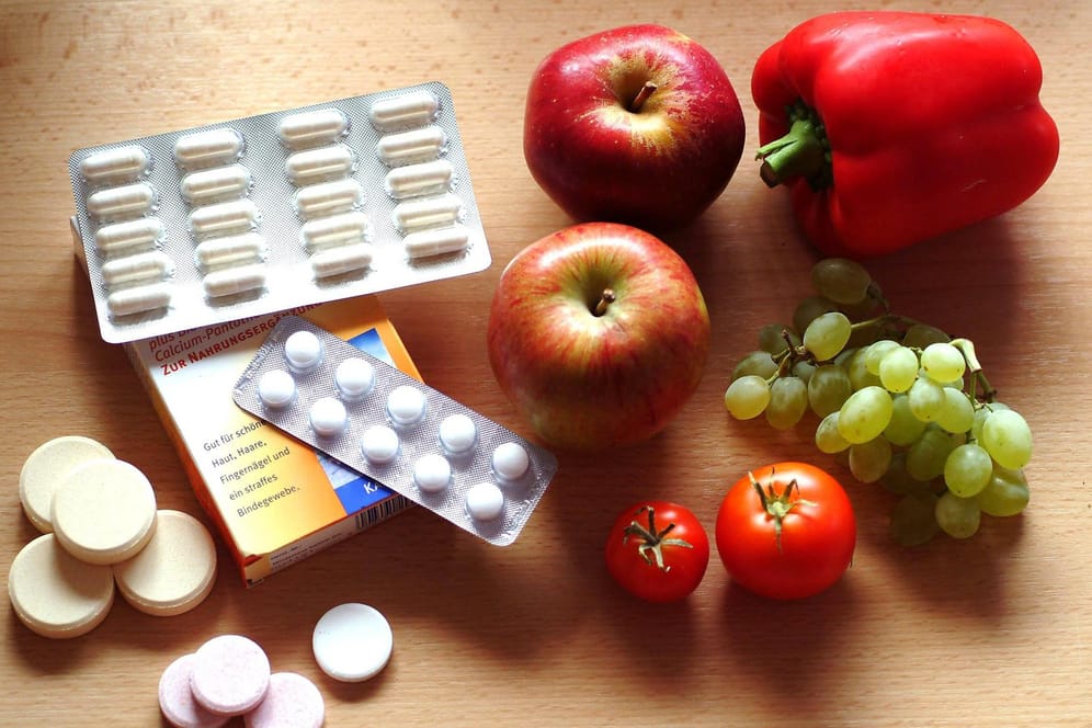 Tabletten und Kapseln neben frischem Obst und Gemüse: Viele Nahrungsergänzungsmittel sind überflüssig für eine gesunde Ernährung.