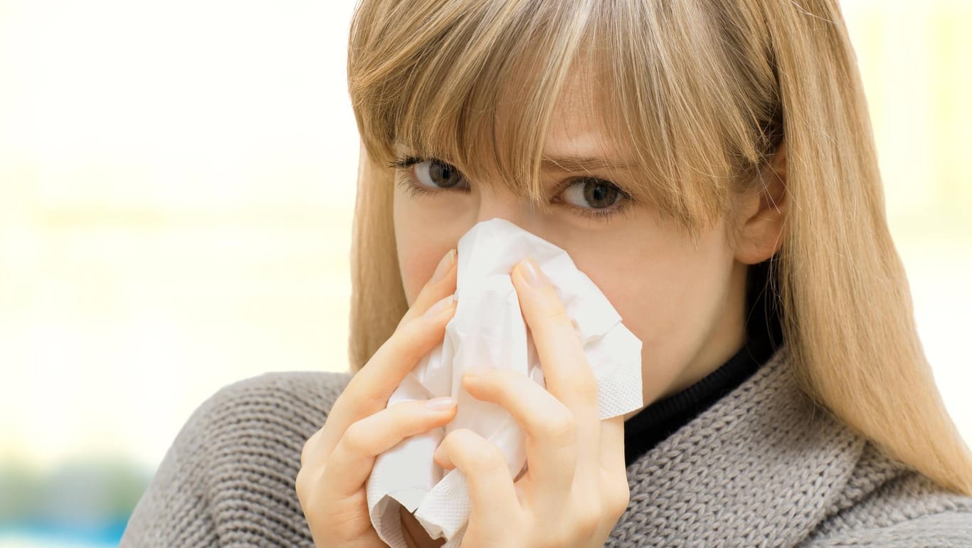 Eine Frau mit einem Taschentuch: Wie verhalten Sie sich auch bei Erkältung möglichst höflich?