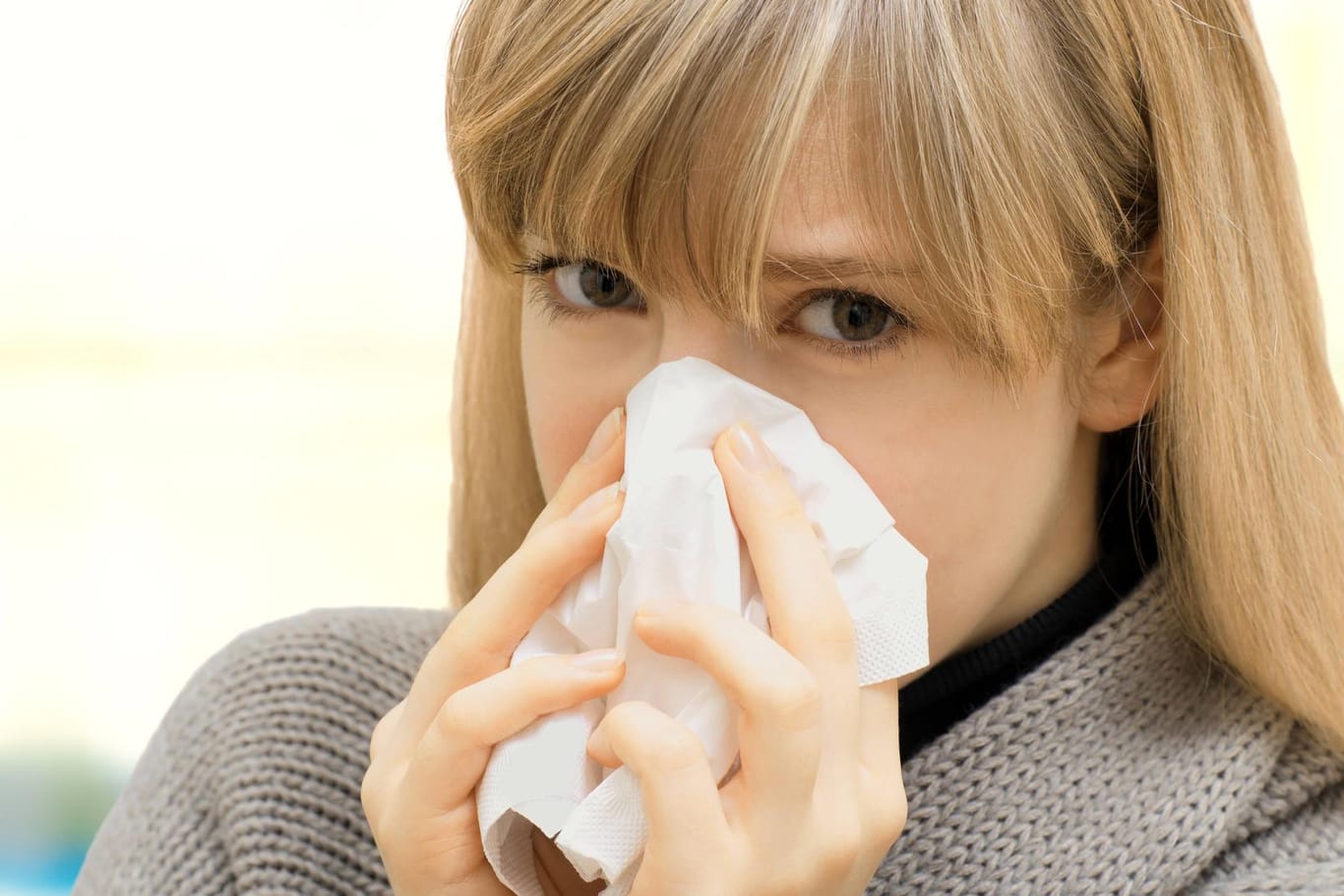 Eine Frau mit einem Taschentuch: Wie verhalten Sie sich auch bei Erkältung möglichst höflich?