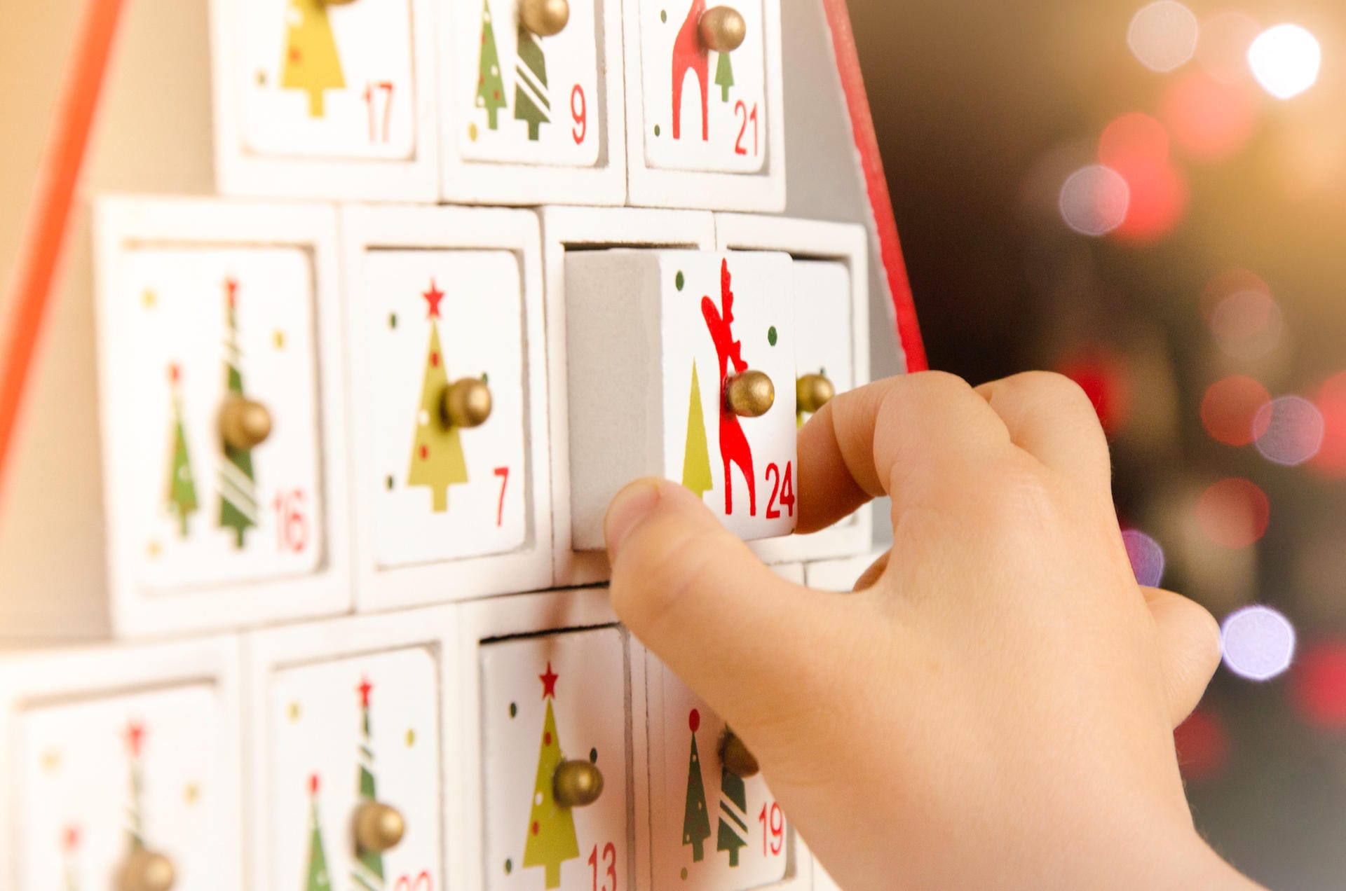 Kinderhand zieht an einem Adventskalender-Fach: Adventskalender aus Holz versprühen einen Hauch Nostalgie. Ob gekauft oder selbst gemacht - Holz macht aus jedem Adventskalender etwas Besonderes. Wer mit kleinen Schachteln basteln möchte, kann alternativ auch Streichholzschachteln nutzen. Mit ihnen sind der Fantasie keine Grenzen gesetzt.