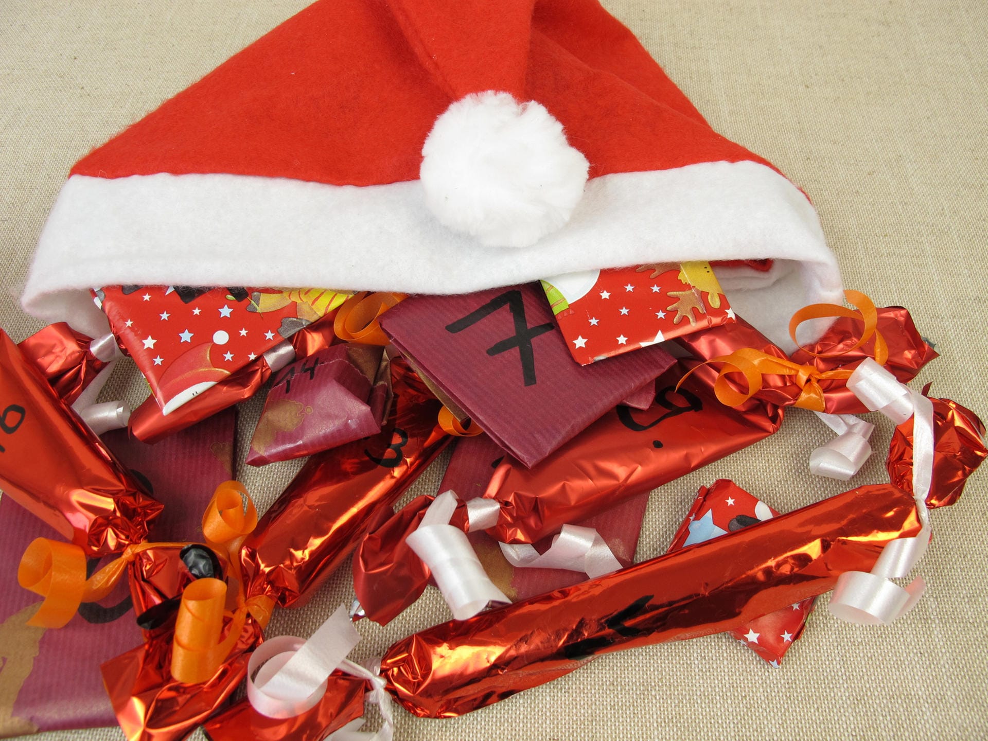 Weihnachtsmütze mit Geschenken: Wer besonders kleine Geschenke in seinen Adventskalender legt, kann auch eine Mütze oder einen kleinen Weihnachtssack zum Aufbewahren der "Türchen" nutzen.