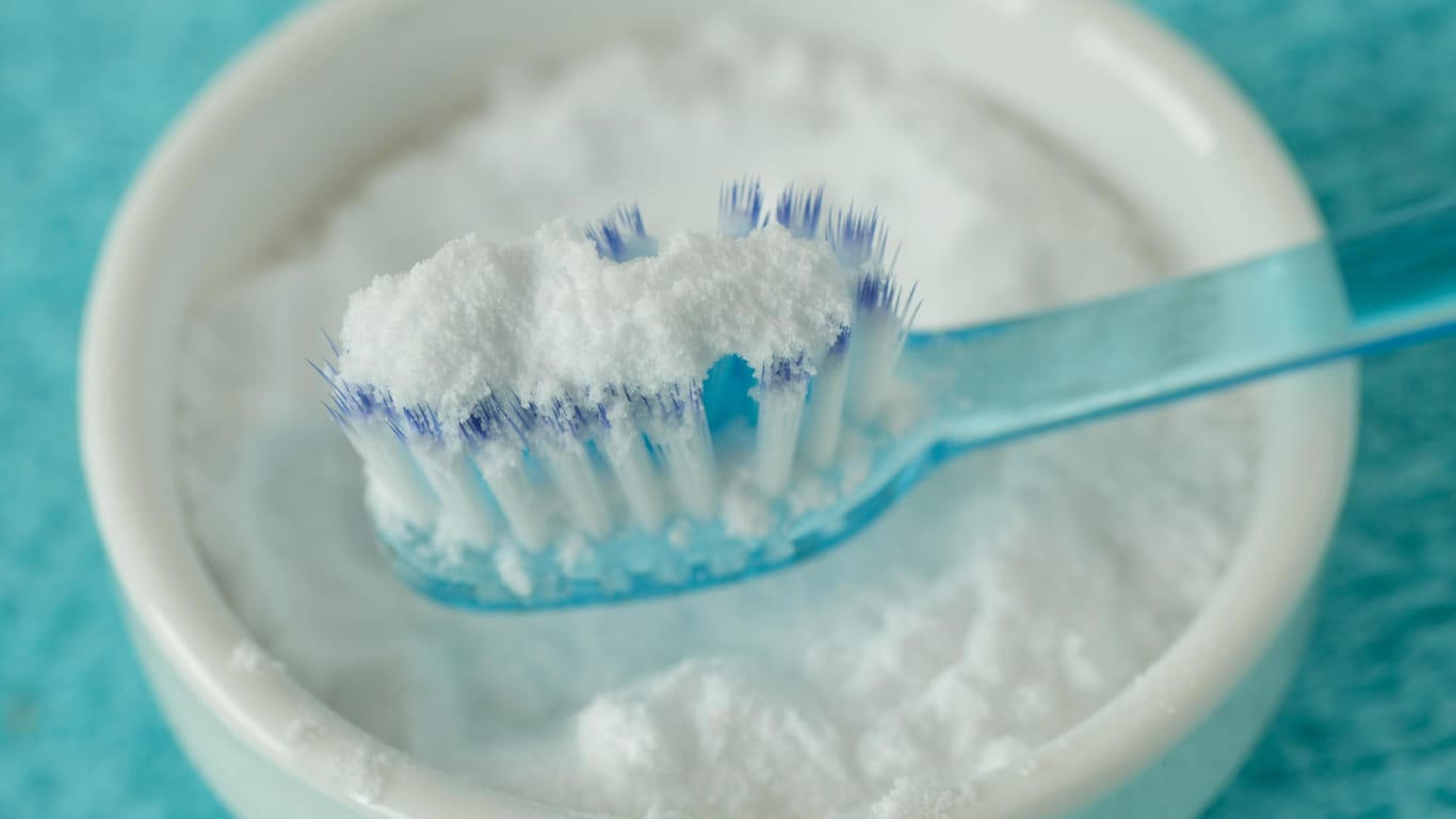 Backpulver auf einer Zahnpasta: Das oft empfohlene Hausmittel schadet den Zähnen auf Dauer mehr als dass es hilft.