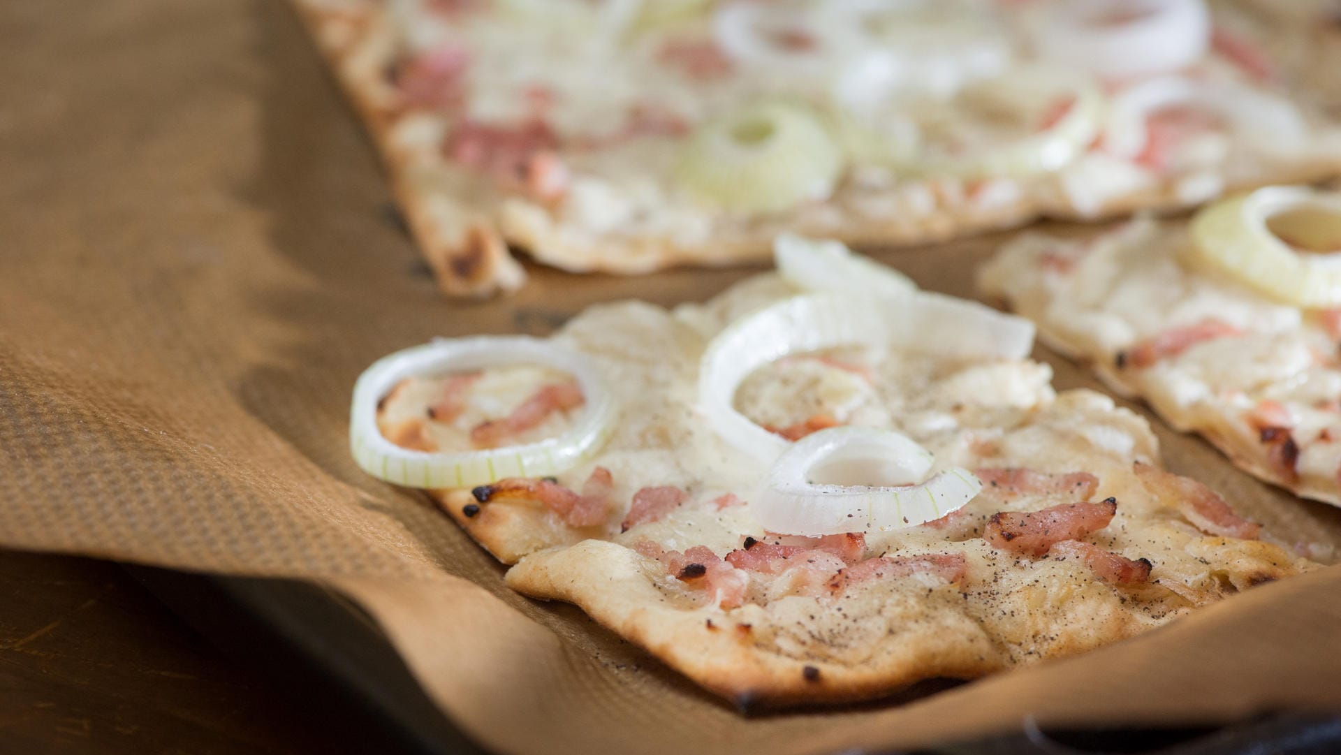 Flammkuchen: Der Klassiker wird mit Zwiebeln und Speck belegt.