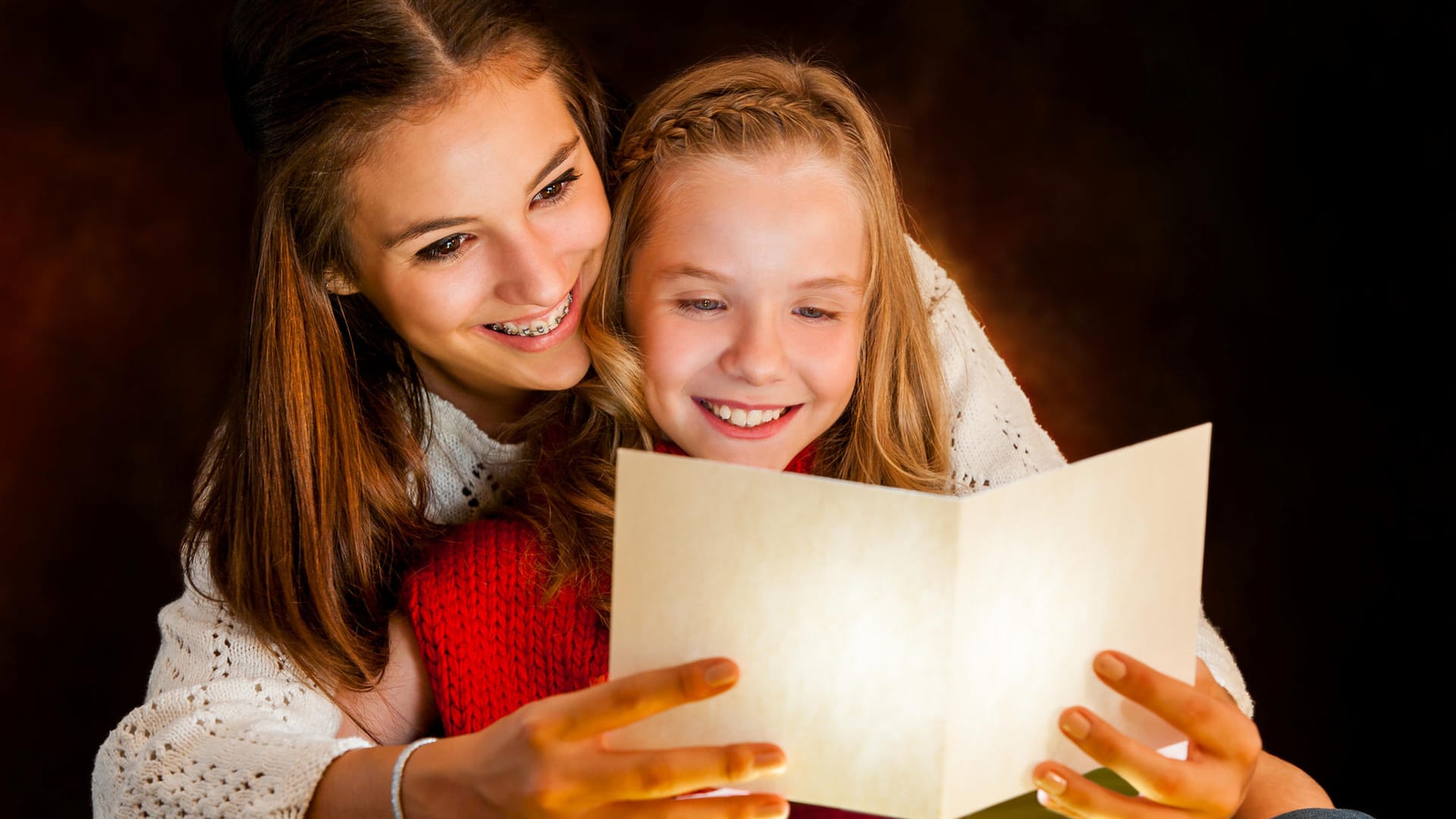 Zwei Mädchen lesen ein Gedicht: Gerade in der Weihnachtszeit gibt es viele schöne Traditionen rund um Gedichte, Lieder und Basteleien.