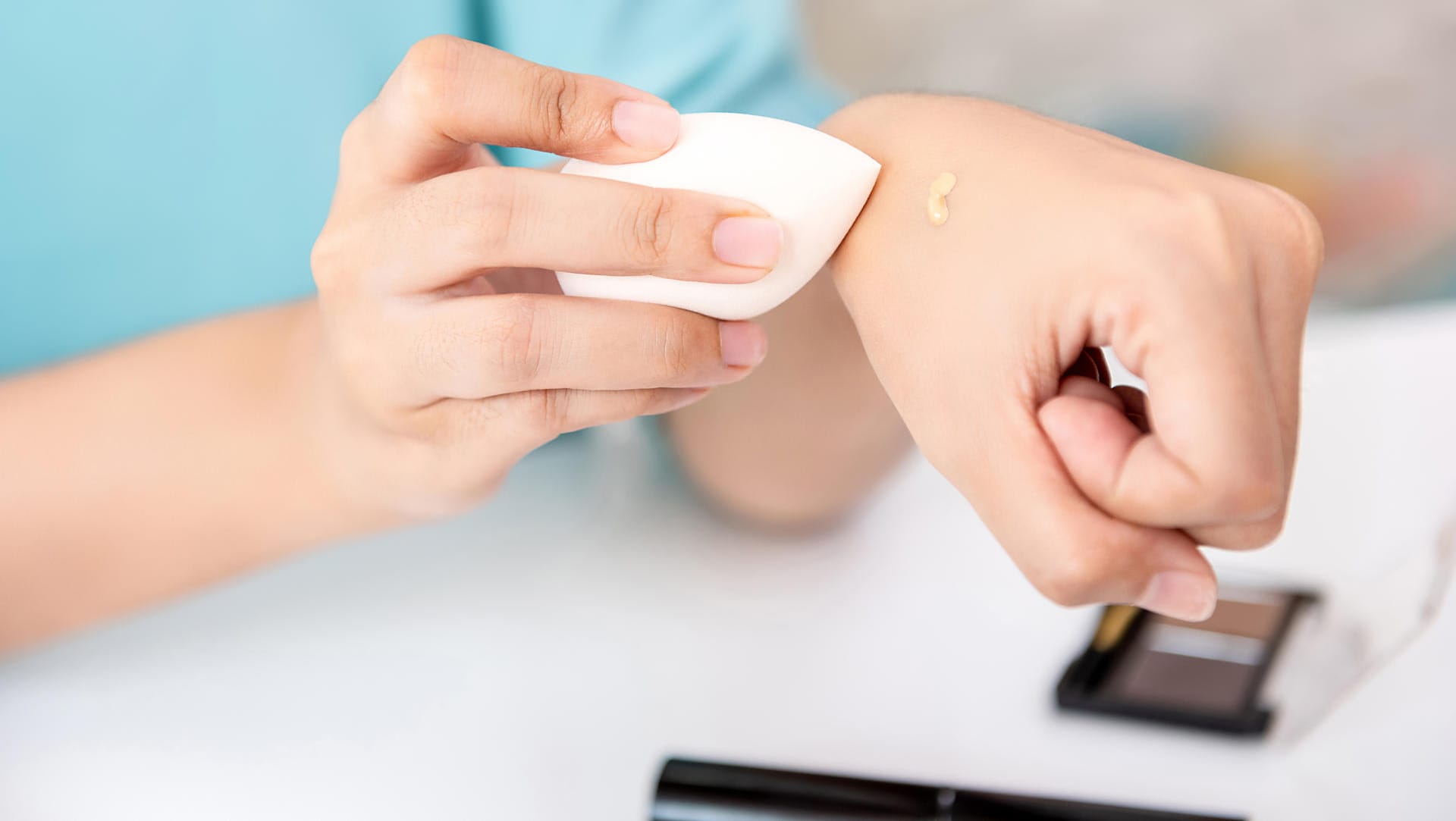 Frau benutzt Beauty Blender, um Make-Up auf der Haut zu verteilen.