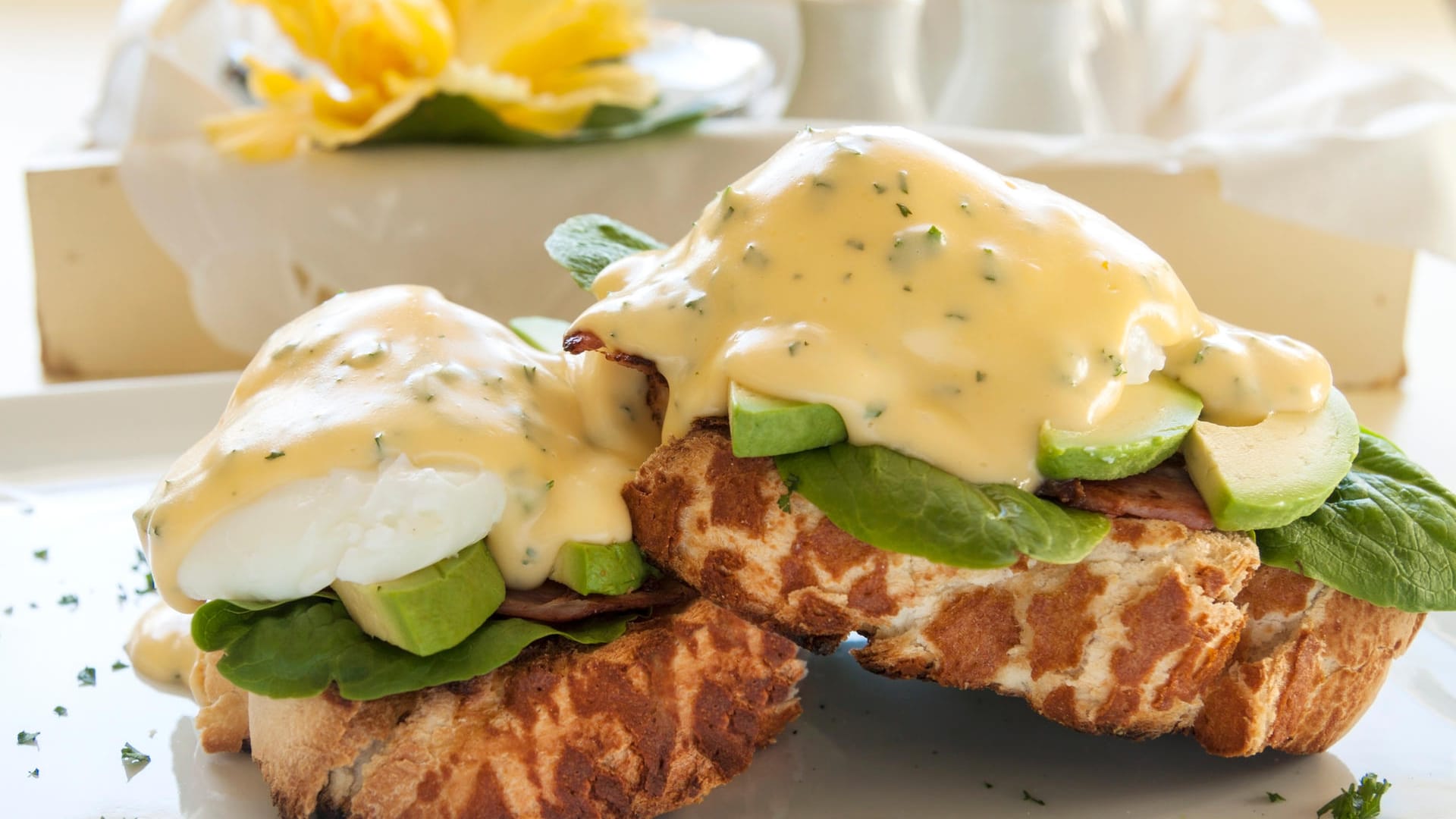 Eggs Benedict: Eine leckere Variation des Gerichts ergibt sich, wenn Sie Avocado und Salatblätter zwischen Ei und Schinken legen.