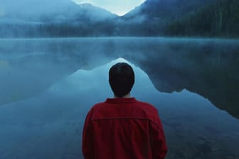 Ein Mann steht am Ufer eines Sees. Menschen mit Depressionen sind unfähig, Freude zu empfinden und fühlen sich leer.