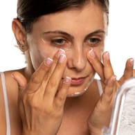 Eine Frau cremt ihr Gesicht ein: Es hängt vom Hautzustand und dem Hauttyp ab, wann man mit einer Antifaltencreme beginnen sollte.