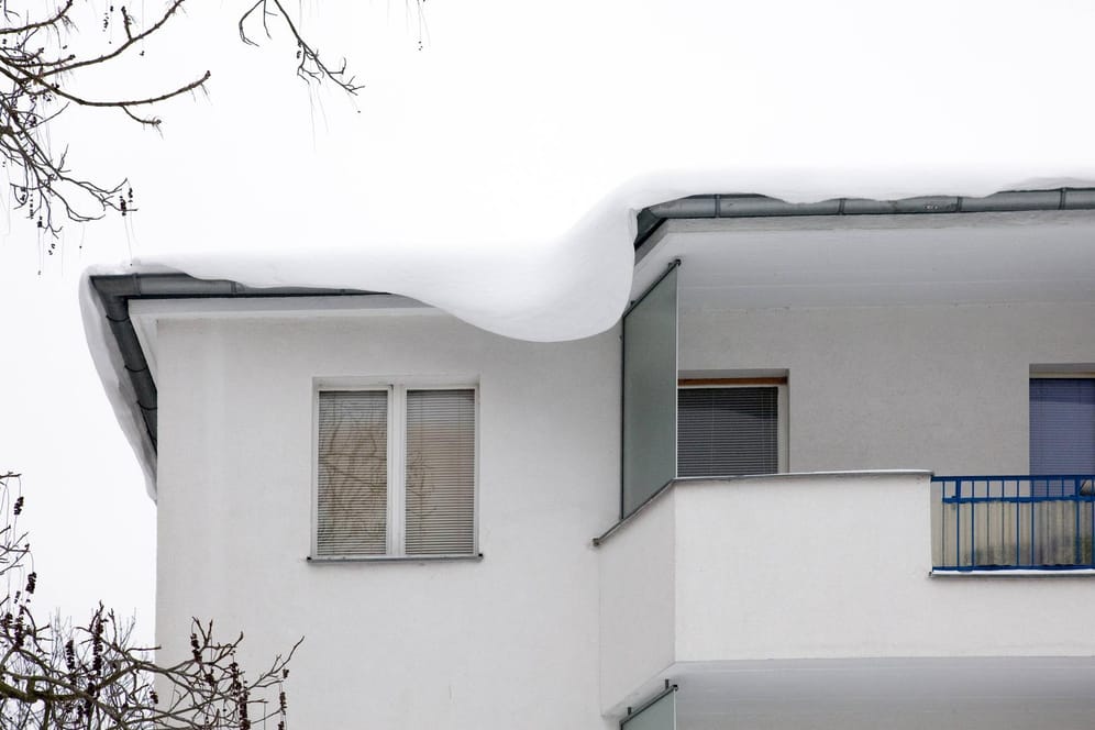 Schneelast auf Dach: Sie belastet die Hausstatik und gefährdet Passanten sowie parkende Autos. (Symbolfoto)