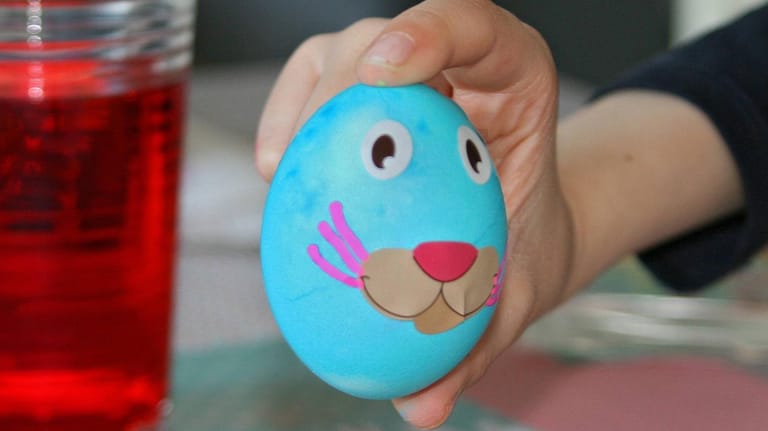 Osterei: Um das Ei wie einen Hasen zu gestalten, färben Sie es zuerst in einer Farbe. Lassen Sie es gut trocknen, danach können Sie ein Gesicht malen. Wenn Sie mögen, können Sie Ohren oder eine Nase aus Papier auf das Ei kleben.