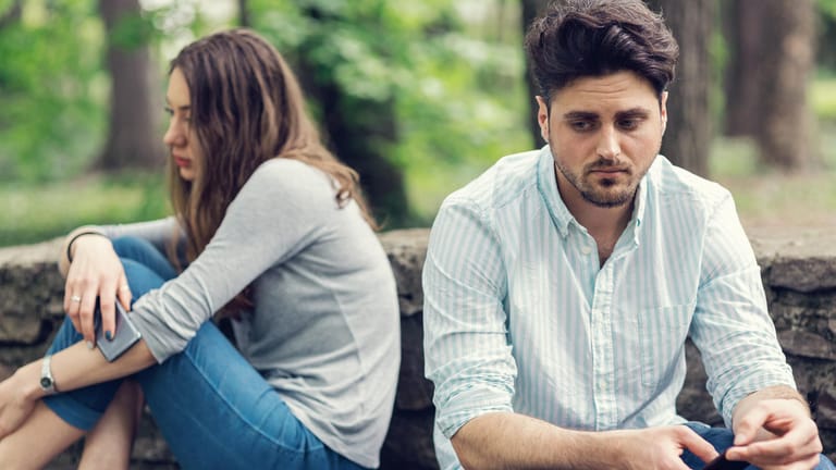 Ein traurig blickendes Paar sitzt voneinander abgewandt. Wie Menschen auf Stress und Erschöpfung reagieren, ist individuell unterschiedlich und hängt auch vom Geschlecht ab.