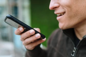 Ein Mann spricht eine Sprachnachricht in sein Handy: Mit einem einfachen Kniff können Anrufer direkt die Mailbox erreichen.