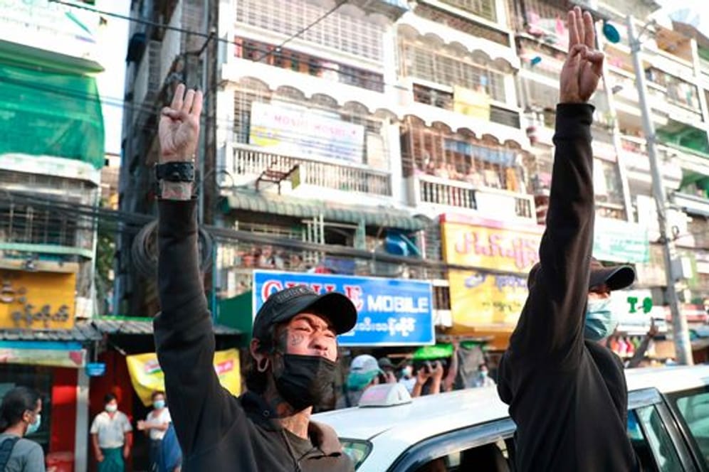 Zwei Männer erheben die Hände zu einem Drei-Finger-Gruß, als Zeichen des Widerstandes, aus Protest gegen den Militärputsch.