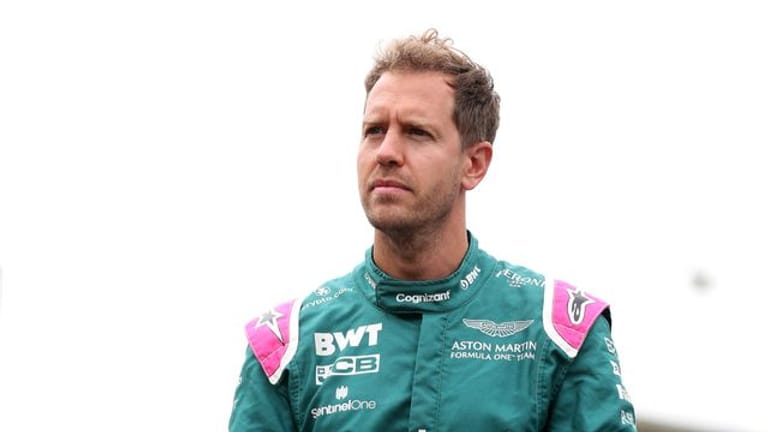 Aston Martin-Pilot Sebastian Vettel steht mit nachdenklicher Miene im Fahrerlager.