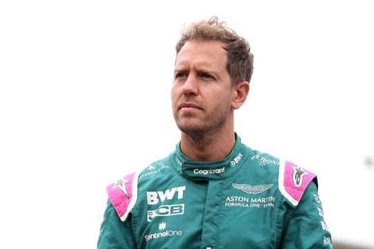 Aston Martin-Pilot Sebastian Vettel steht mit nachdenklicher Miene im Fahrerlager.