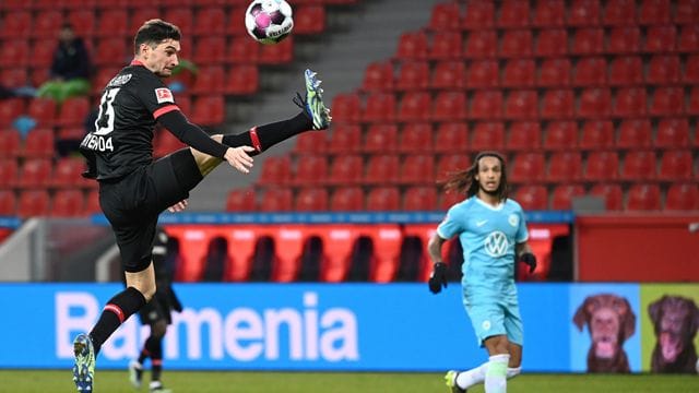 Leverkusens Lucas Alario (l) nimmt den Ball artistisch in der Luft an.