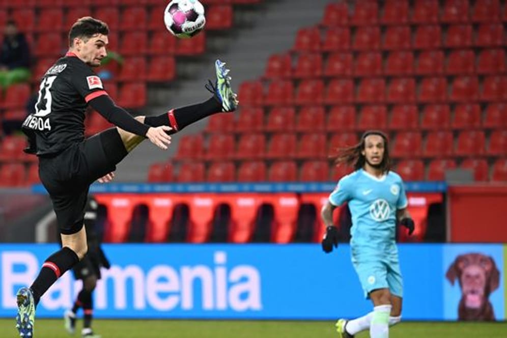 Leverkusens Lucas Alario (l) nimmt den Ball artistisch in der Luft an.