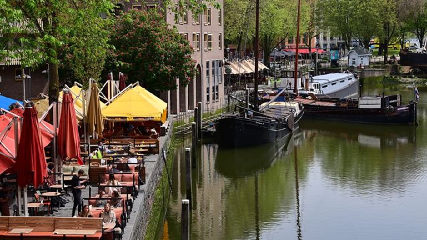 Nur wenige Gäste sitzen bei sonnigem Wetter in den Außenbereichen der Cafés und Restaurants am Historischen Hafen in Rotterdam (Archivbild).