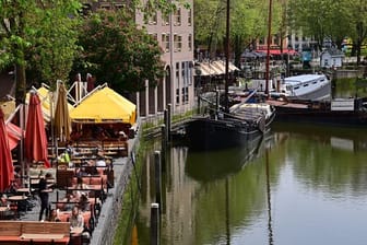 Nur wenige Gäste sitzen bei sonnigem Wetter in den Außenbereichen der Cafés und Restaurants am Historischen Hafen in Rotterdam (Archivbild).