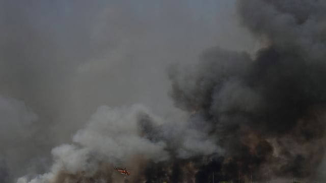 Ein Hubschrauber fliegt über einen Waldbrand nördlich von Athen. Ein Hubschrauber fliegt über einen Waldbrand nördlich von Athen.