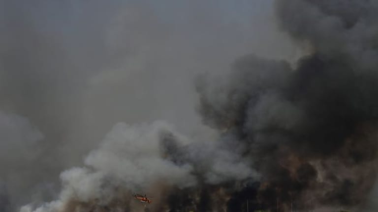 Ein Hubschrauber fliegt über einen Waldbrand nördlich von Athen.