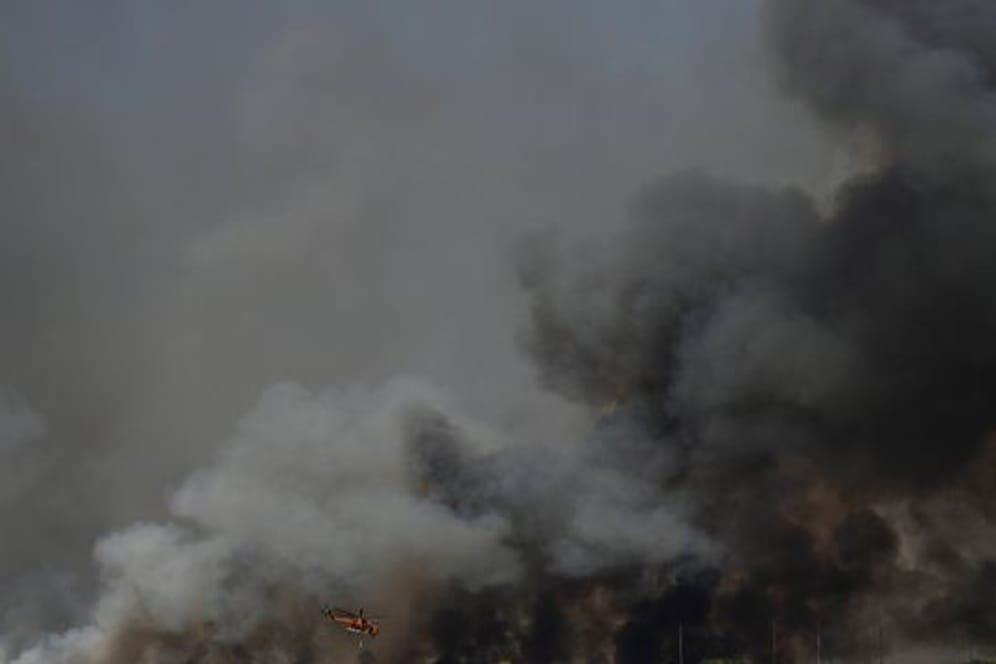 Ein Hubschrauber fliegt über einen Waldbrand nördlich von Athen.