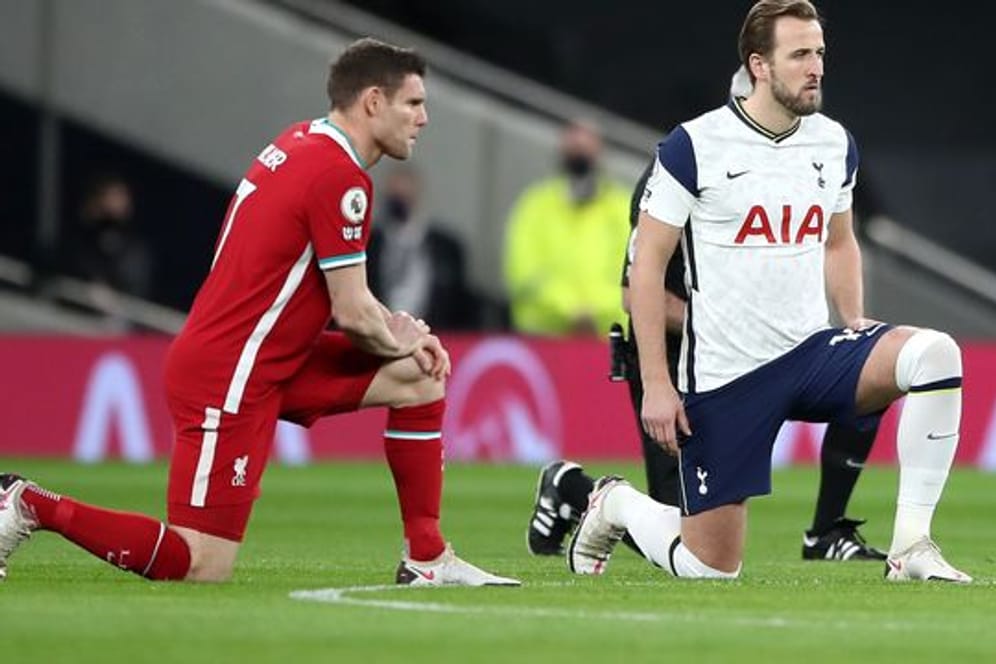 Liverpools James Milner (l) und Tottenhams Harry Kane knien vor einem Premier-League-Spiel auf dem Rasen.