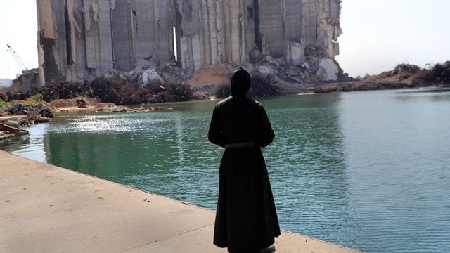 Ein Priester sieht im Hafen von Beirut auf die bei der Explosion vor einem Jahr zerstörten Getreidesilos.