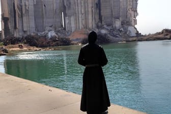 Ein Priester sieht im Hafen von Beirut auf die bei der Explosion vor einem Jahr zerstörten Getreidesilos.