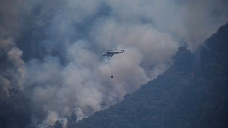 Ein Hubschrauber transportiert im türkischen Turgut Löschwasser zu einem Waldbrand.