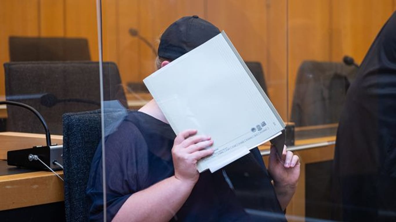 Zu Beginn des Prozesses im Missbrauchskomplex Münster sitzt die Mutter eines Opfers im Landgericht Münster und verdeckt ihr Gesicht mit einer Mappe.