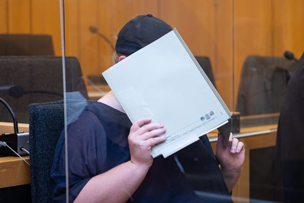 Zu Beginn des Prozesses im Missbrauchskomplex Münster sitzt die Mutter eines Opfers im Landgericht Münster und verdeckt ihr Gesicht mit einer Mappe.