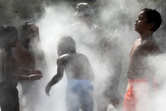 Kinder erfrischen sich im Nebel eines Brunnens auf dem Rose Kennedy Greenway in Boston.