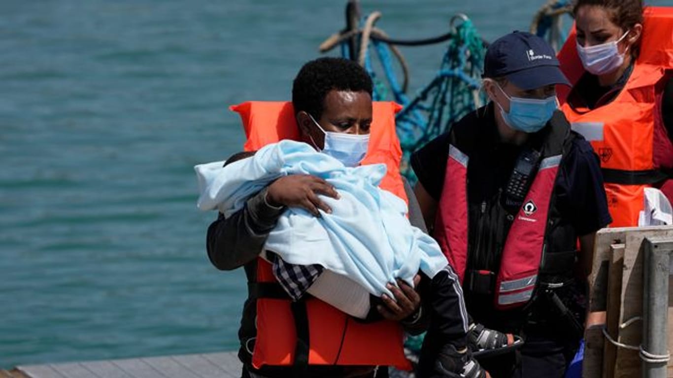 Ein Migrant hält ein Kind im Arm, während er im Hafen von Dover ankommt, nachdem er im Kanal von britischen Grenzbeamten aufgegriffen wurde.