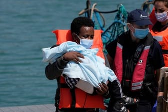 Ein Migrant hält ein Kind im Arm, während er im Hafen von Dover ankommt, nachdem er im Kanal von britischen Grenzbeamten aufgegriffen wurde.