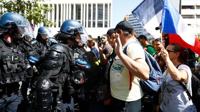 Bei einer Protestveranstaltung gegen die verschärfte Nachweispflicht stehen sich in Paris Demonstranten und Polizisten gegenüber. Bei einer Protestveranstaltung gegen die verschärfte Nachweispflicht stehen sich in Paris Demonstranten und Polizisten gegenüber.