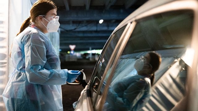 Eine Helferin testet Insassen eines Autos im "Testzentrum am Zoo" in Hannover. Eine Helferin testet Insassen eines Autos im "Testzentrum am Zoo" in Hannover.