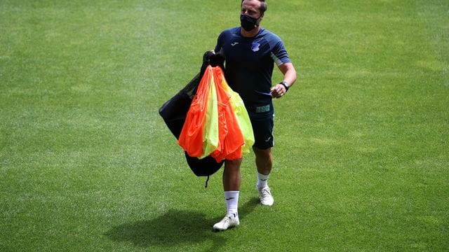 Gabor Gallai, Trainer der Frauen-Mannschaft der TSG Hoffenheim, geht vor einem Spiel mit Leibchen in der Hand über den Platz.