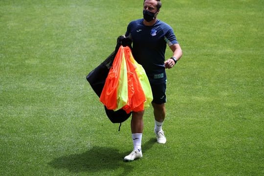 Gabor Gallai, Trainer der Frauen-Mannschaft der TSG Hoffenheim, geht vor einem Spiel mit Leibchen in der Hand über den Platz.