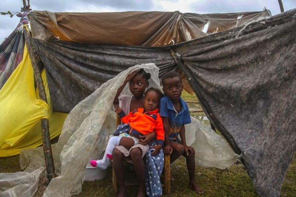 Kinder versuchen in Les Cayes, sich mit einer Plane vor dem Regen zu schützen.