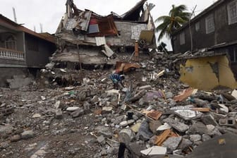 Ein junger Mann sucht in den Trümmern eines eingestürzten Gebäudes.