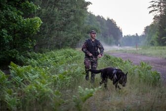 Ein Mitglied des litauischen Grenzschutzes patrouilliert im Juni mit einem Hund an der Grenze zu Belarus.