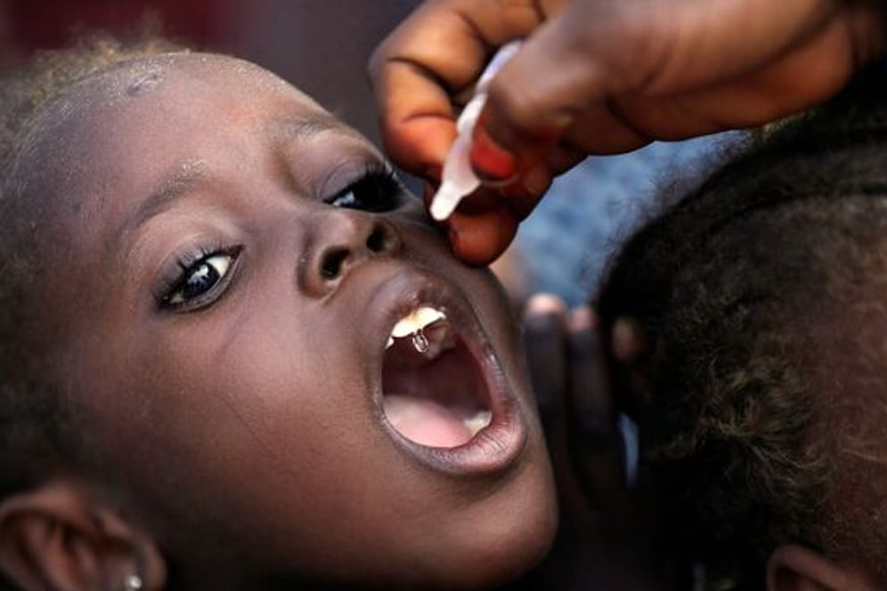Eine Mitarbeiterin des Gesundheitswesens impft ein kleines Mädchen gegen Polio in einem Lager für Geflüchtete in Nigeria.